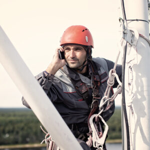 tower technician talking on a cell phone on a telecommunications tower. the concept of checking cellular signal. Copy space for your text
