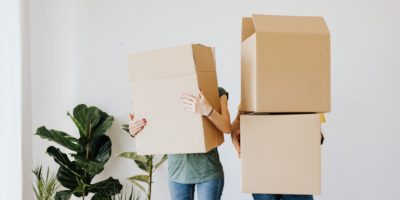 young couple holding boxes moving in