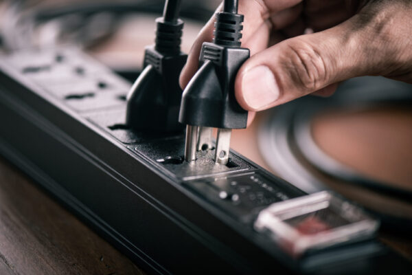 Electrical power strip Closeup of a mans hand inserting a plug into electrical power strip.