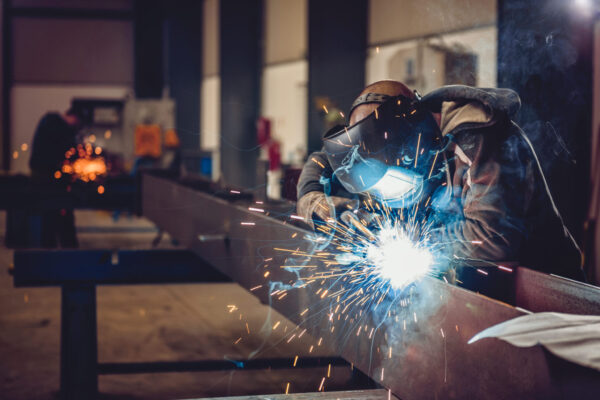 Industrial Welder With Torch Industrial Welder With Torch and Protective Helmet in big hall welding metal profiles