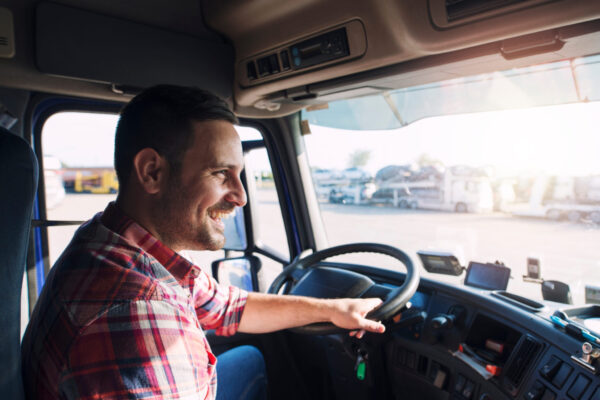 Professional middle aged truck driver in casual clothes driving Professional middle aged truck driver in casual clothes driving truck vehicle going for a long transportation route.