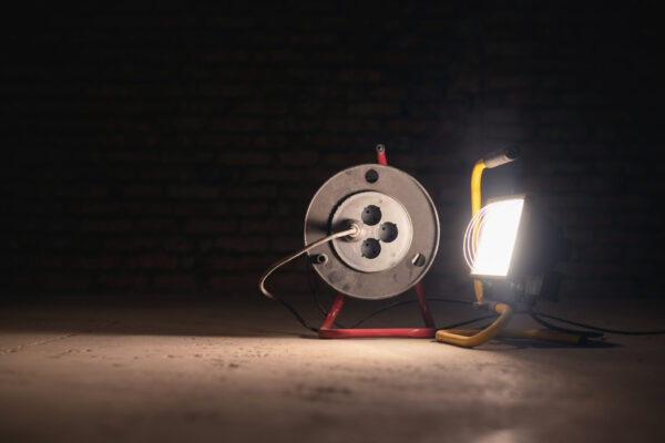 Spotlight lamp and electric power extension cord on the construction site room background. Spotlight lamp and electric power extension cord on the construction site room background.