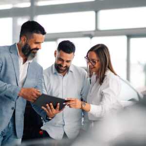 Professional car dealer advising satisfied couple in showroom. In a sleek car showroom, a professional dealer offers advice and insight to an intrigued couple, enhancing customer satisfaction and decision-making with expert knowledge.