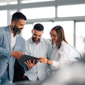 Professional car dealer advising satisfied couple in showroom. In a sleek car showroom, a professional dealer offers advice and insight to an intrigued couple, enhancing customer satisfaction and decision-making with expert knowledge.