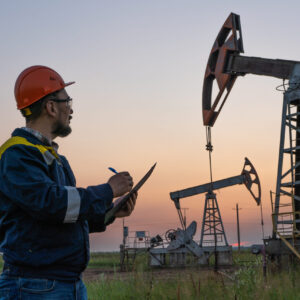 Oil worker checks an oil rig at sunset. Maintenance of oil pump jacks Oil worker checks an oil rig at sunset. Maintenance of oil pump jacks